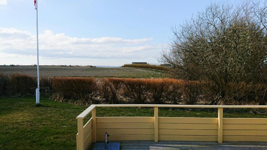 une clôture en bois avec un champ en arrière-plan dans l'établissement Charming Wooden Cottage Close To Handbjerg Beach, à Vinderup