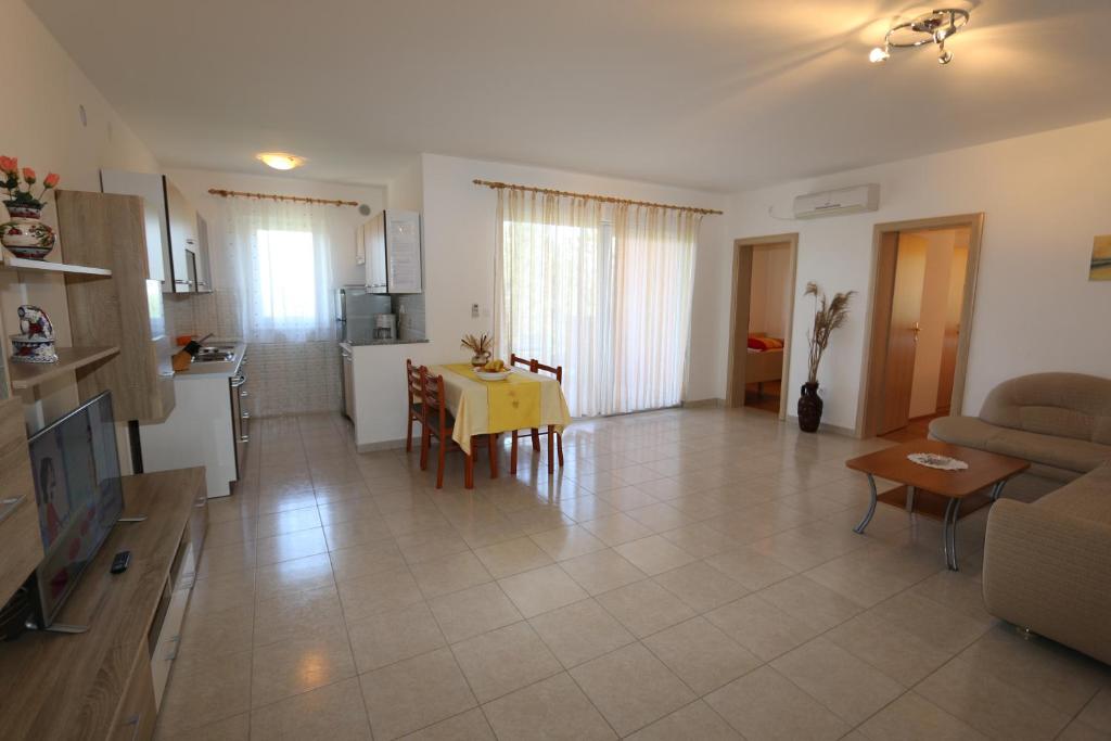a living room with a yellow table and a kitchen at Apartments Dudovic in Šilo