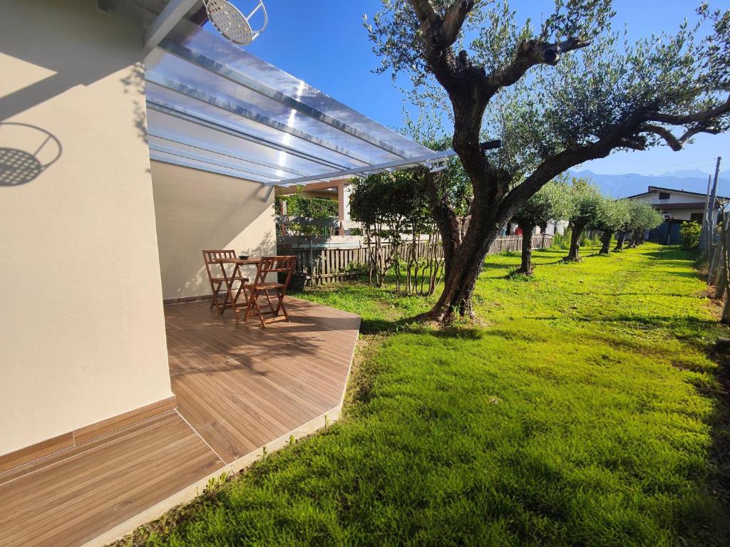 une terrasse en bois avec une table et un arbre dans l'établissement Il Posticino House in Marina, Garden and Veranda, à Marina di Massa