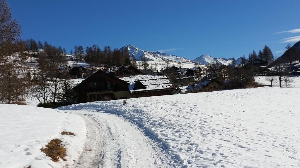 pokryta śniegiem droga z wioską w tle w obiekcie Monolocale Milky Way - Sestriere w mieście Sestriere