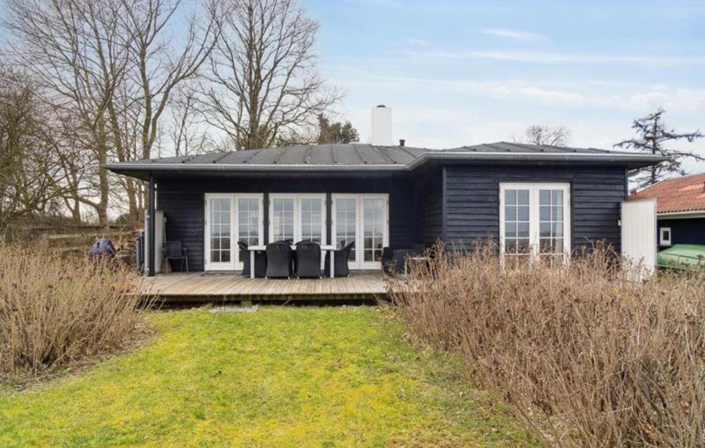 a small black house with a porch and a yard at Beachfront Summerhouse With Amazing View And Peace in Hesselager