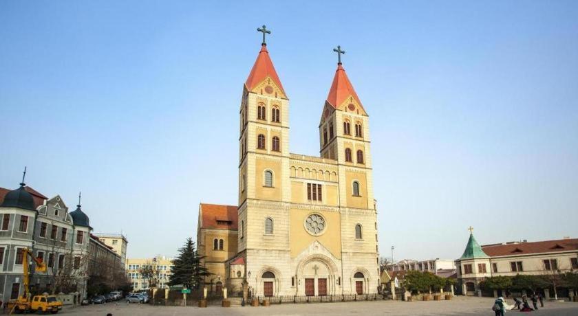 a church with a tower with a clock on it at 7 Days Premium Qingdao Railway Station Zhanqiao Badaxia Plaza in Qingdao