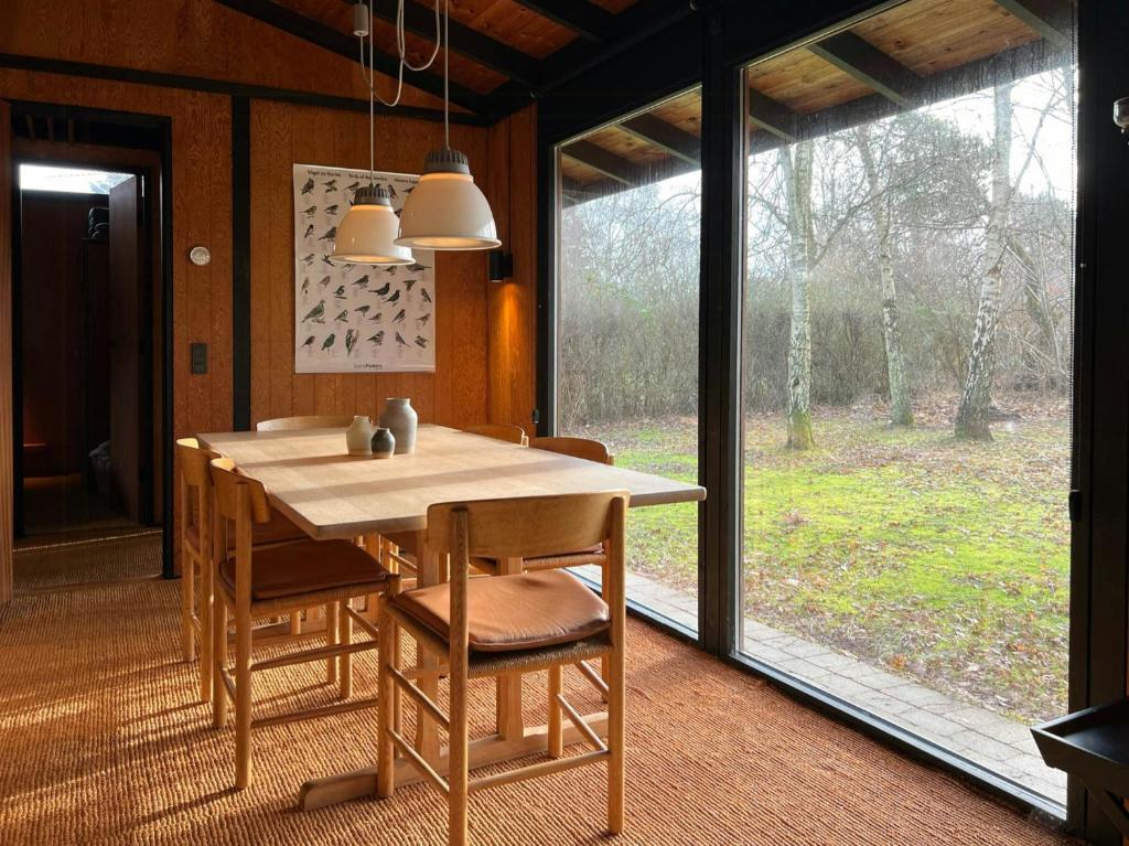Un comedor con mesa y sillas y una ventana. en Original 70S Home Surrounded By Woods, en Vejby