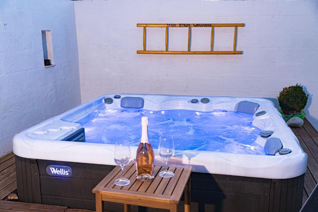 a large jacuzzi tub with wine glasses and a wooden table at Villa Italo Spa - Wine Tasting - Parking Car in Ostuni