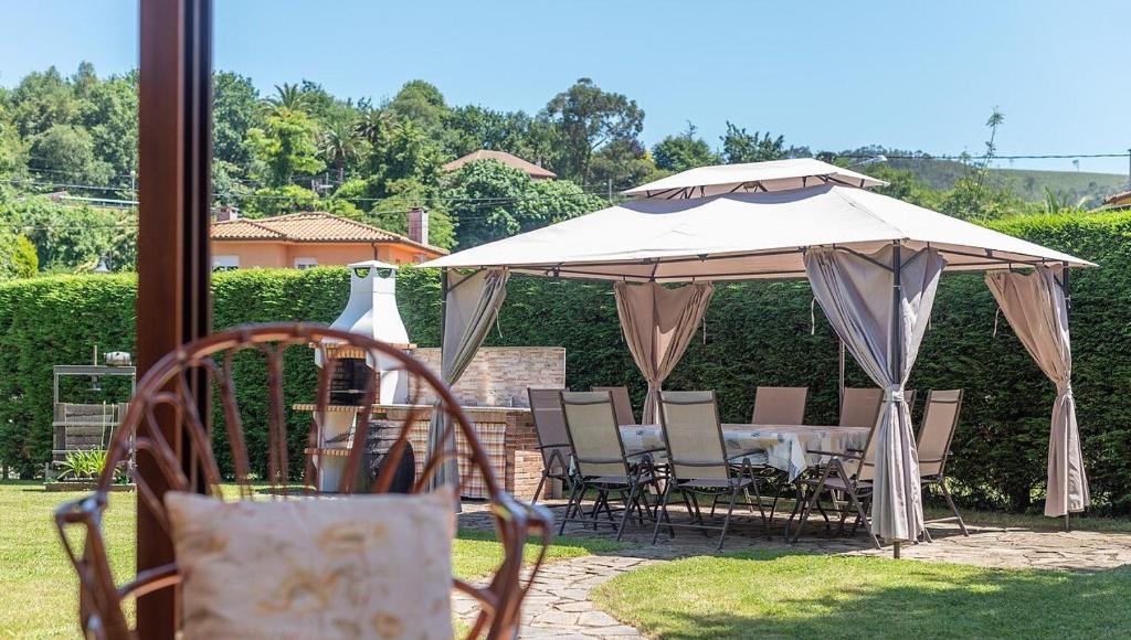 a table and chairs under an umbrella in a yard at FINCA LA GRANDA DE LA CONCHA in Nueva de Llanes