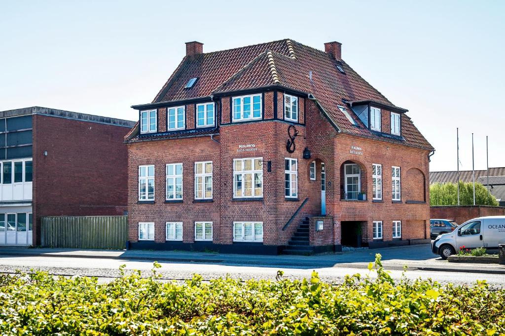 een groot gebouw van rode baksteen met een gambrel dak bij Villa Gertrud in Kolding