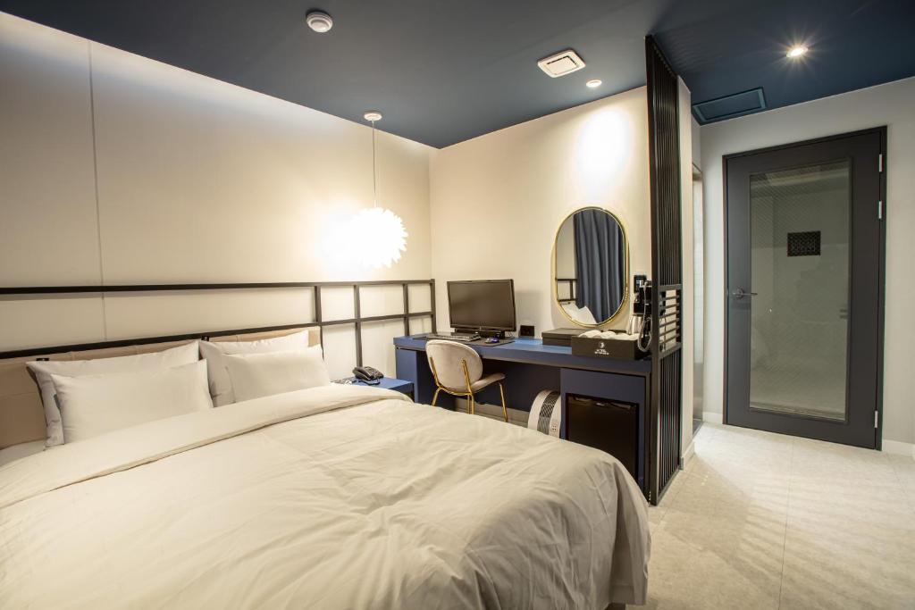 Un dormitorio con una cama y un escritorio con una computadora. en On the Moon Hotel, en Wonju