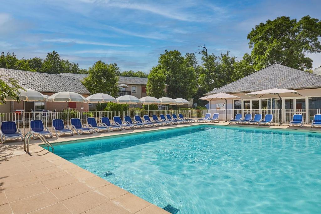 ein großer Pool mit blauen Stühlen und Stühlen in der Unterkunft Résidence Odalys Le Hameau du Lac in Rignac