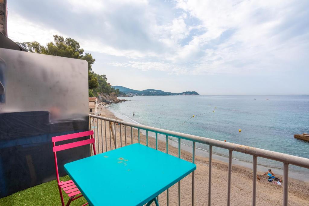 une table bleue et une chaise rouge sur un balcon donnant sur la plage dans l'établissement Les Jeux de Boules 6, au Pradet