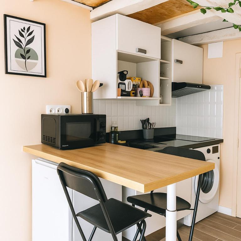 une cuisine avec une table en bois et des chaises noires dans l'établissement Studio Cosy ambiance Tiny House, à Angers