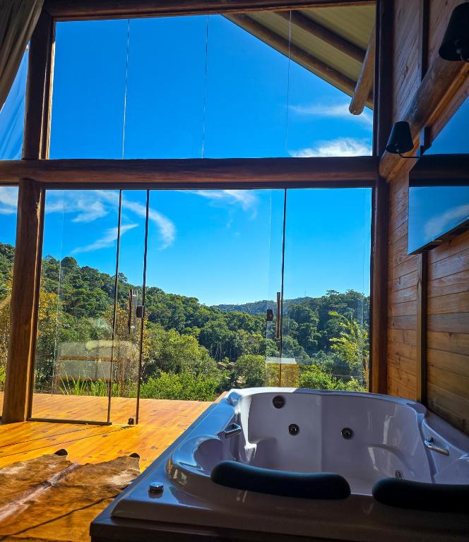 Una bañera en una habitación con una ventana grande. en Chalés Vidal, en Venda Nova do Imigrante