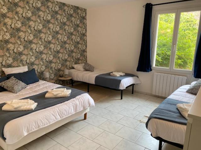 ein Zimmer mit drei Betten und einem Fenster in der Unterkunft Gite l'Amical in Roézé-sur-Sarthe
