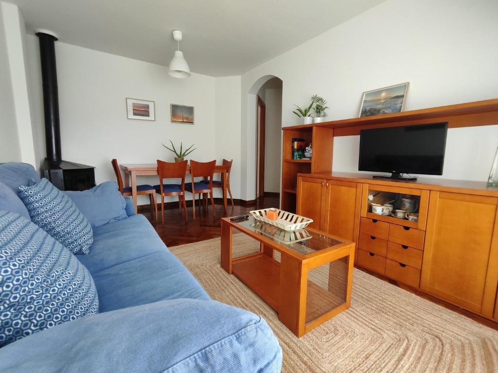 a living room with a blue couch and a tv at Apartamento centro de Sada in Sada