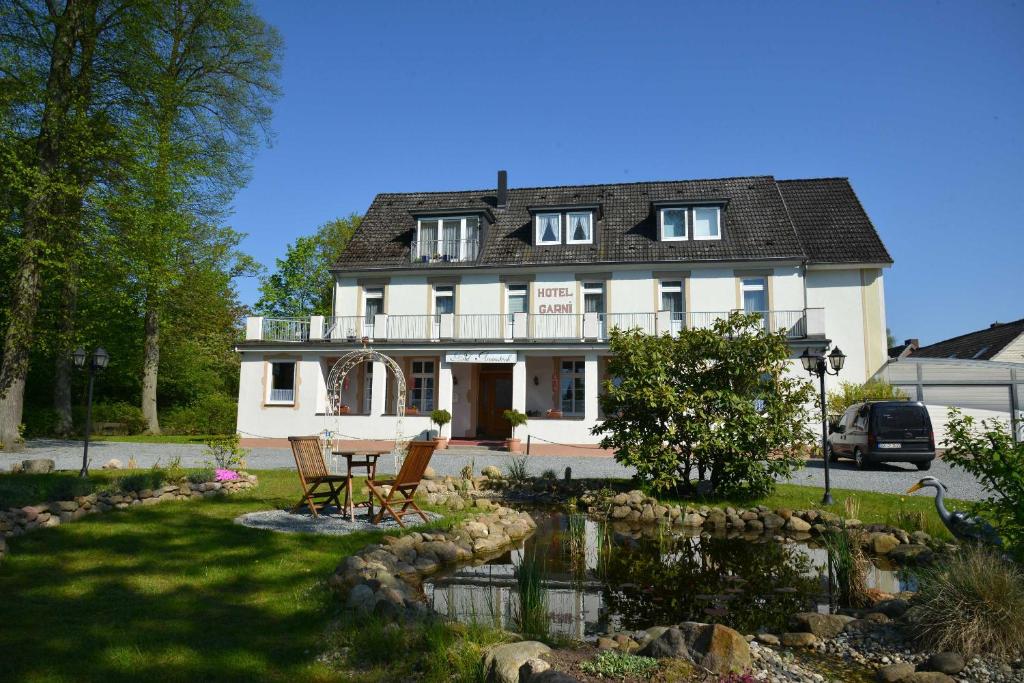 uma casa com um lago em frente em Arnimsruh Hotel garni em Lübeck