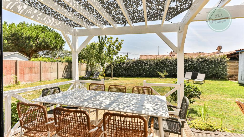 einen Tisch und Stühle unter einer weißen Pergola in der Unterkunft Villa Ocean in Les Bussolleries