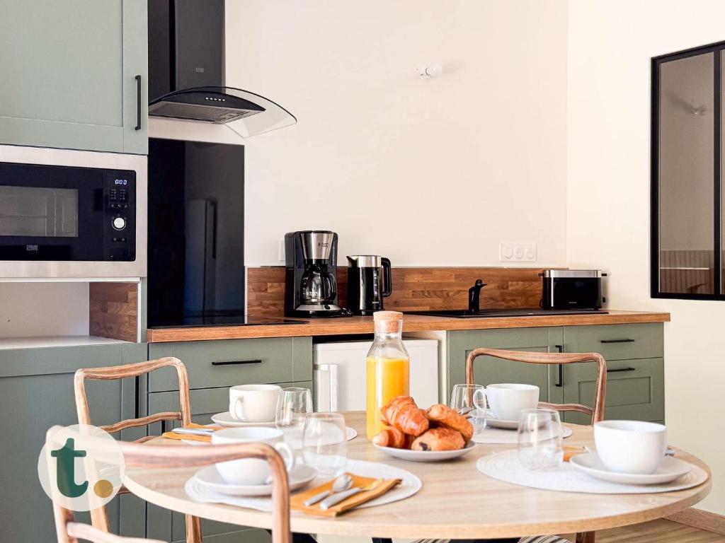 - une cuisine avec une table et une plaque de cuisson dans l'établissement Tranquiloue - Appart Centre-Ville - Puy du Fou 20min, aux Herbiers