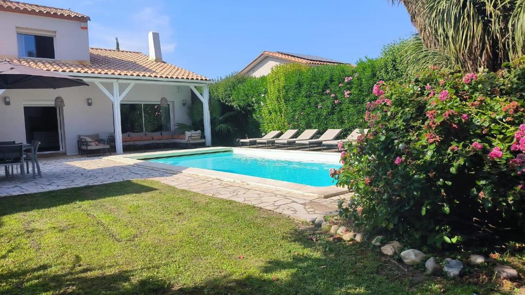 une cour arrière avec une piscine et une maison dans l'établissement VILLA de charme avec piscine et jardin en bord de mer, à Saint-Cyprien