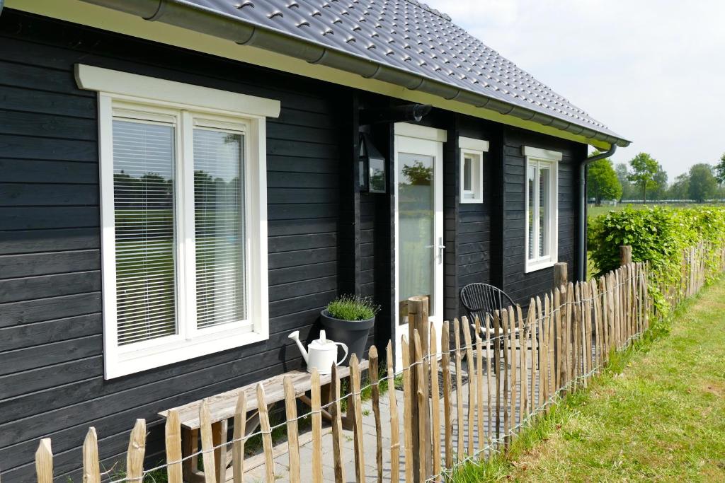 een zwart huis met een houten hek ervoor bij Gastenverblijf De Rozenkamp in Epe