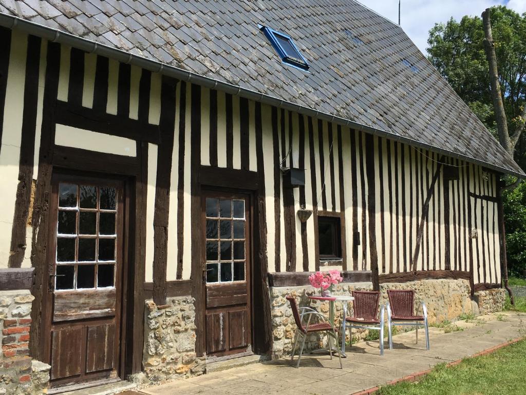 un vieux bâtiment avec une table et des chaises à l'extérieur dans l'établissement Le gîte du Manoir Normand, à Saint-Philbert-des-Champs
