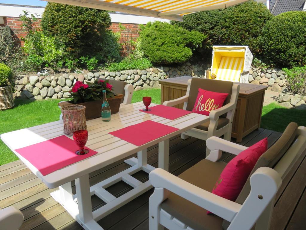 a wooden table and chairs on a deck with a table and chairs at Ferienhaus Horstweg 5 in Tinnum