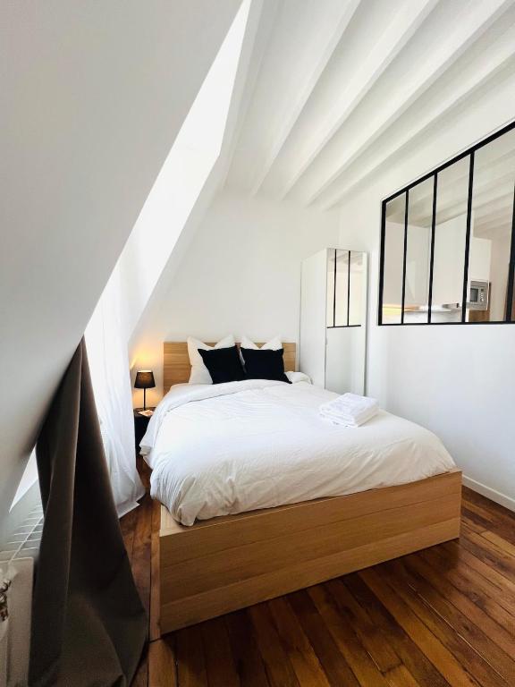 une chambre avec un grand lit blanc avec des oreillers noirs dans l'établissement Welcome to Montmartre, à Paris