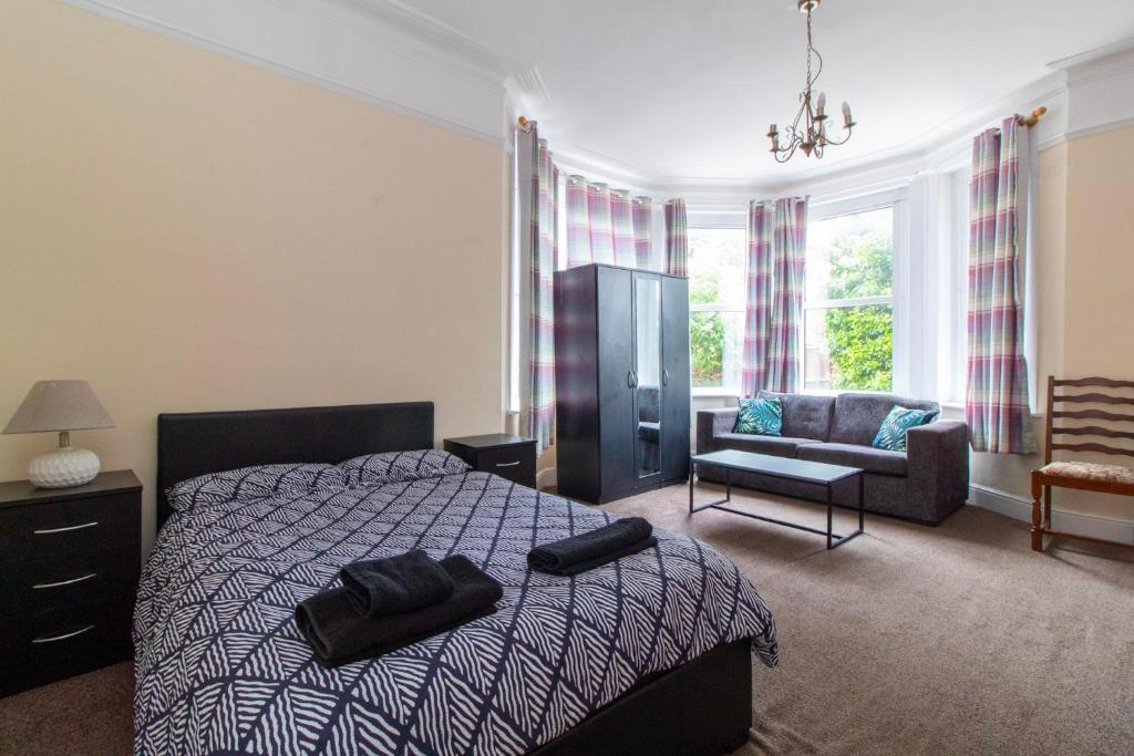 a bedroom with a bed and a couch and a chair at Thornbury Guest House Room 1 in Southampton