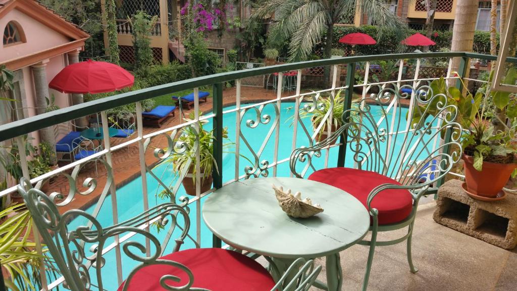a table and chairs on a balcony with a pool at Woodmere Serviced Apartment in Nairobi