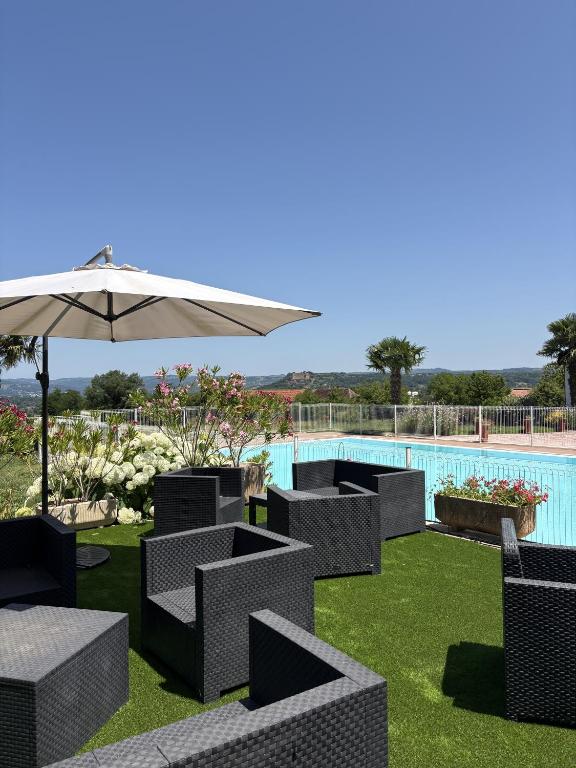 Un grupo de sillas y una sombrilla junto a una piscina. en Domaine de PY, en Loubressac