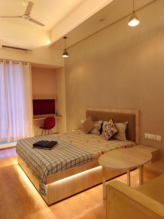 a bedroom with a large bed and a table at Gaur City Mall Homestay in Ghaziabad
