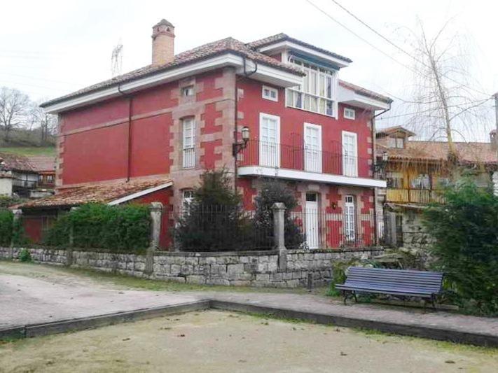 a red house with a bench in front of it at Posada El Marqués De Trancadorio in La Virgen