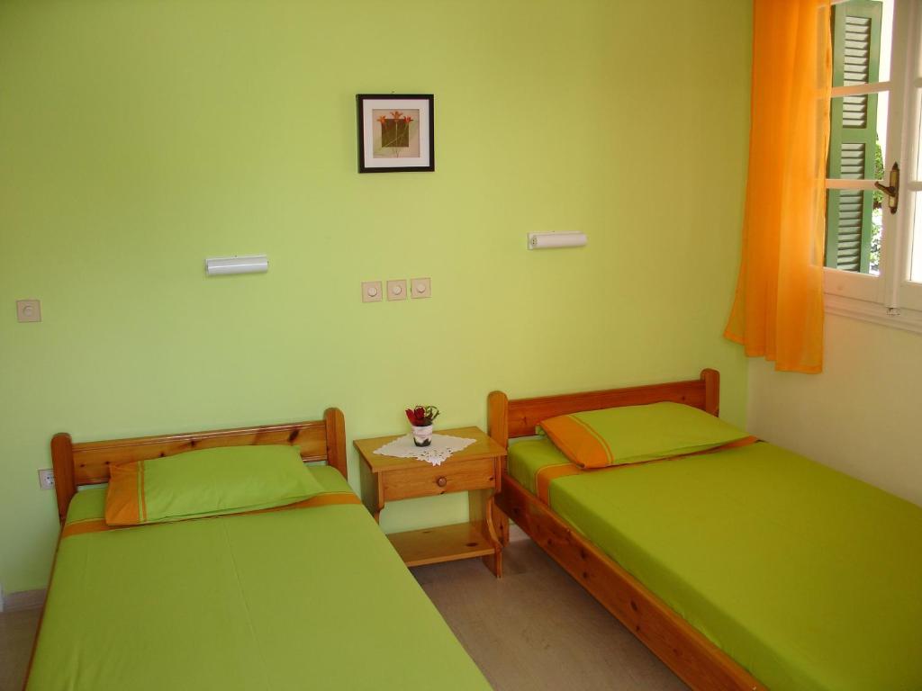 two beds in a room with green walls at Lena Blue Sea Apartments in Kalami