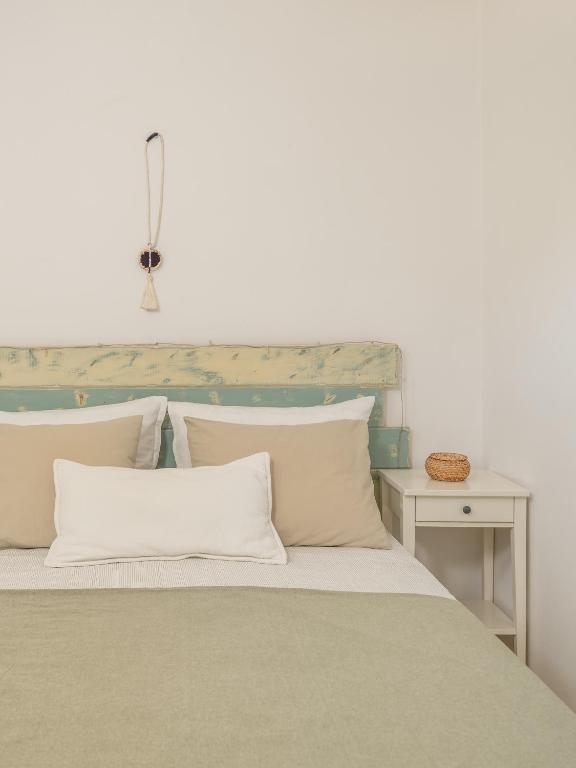 a bed with white pillows and a table with a lamp at Serifos Dream Houses near the sea in Ganema