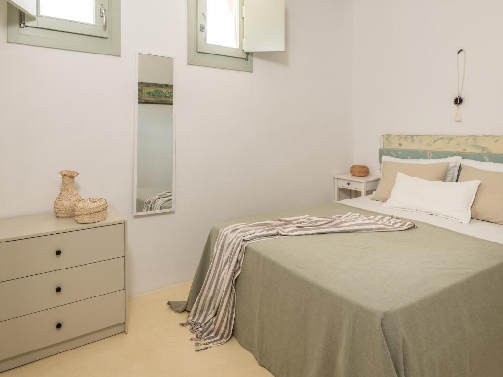a bedroom with a bed and a dresser and windows at Serifos Dream Houses near the sea in Ganema
