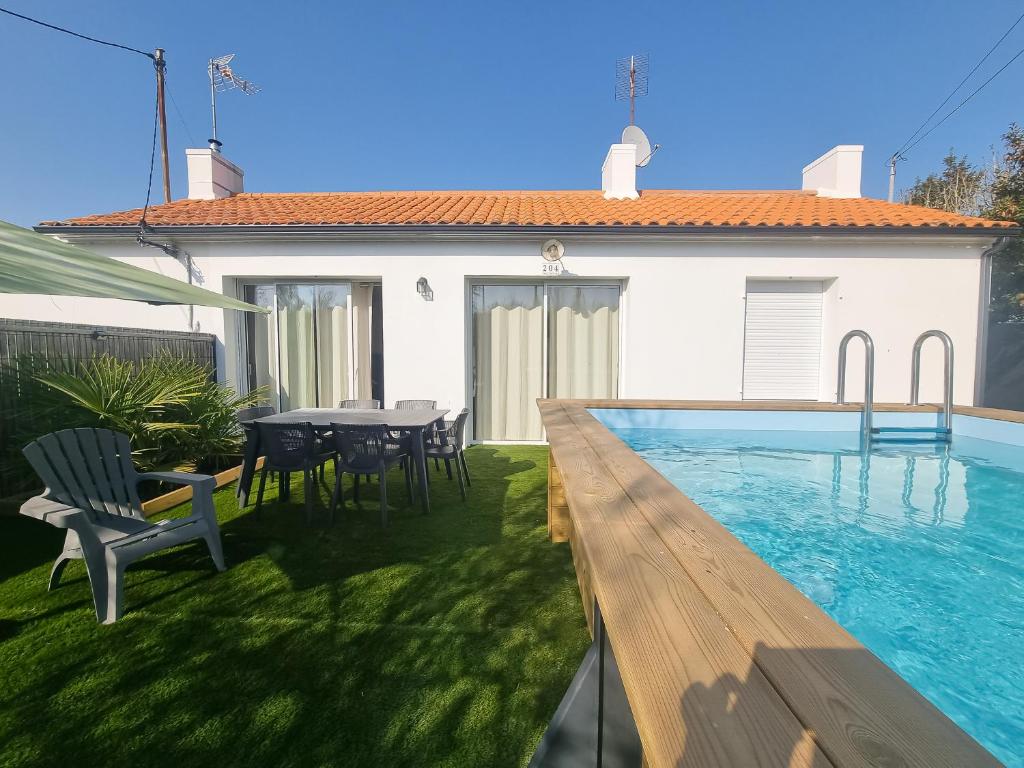une cour arrière avec une piscine, une table et des chaises dans l'établissement La Maraîchine Ensoleillée, à Saint-Jean-de-Monts