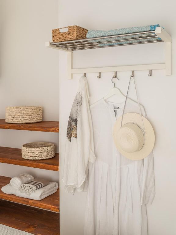 a closet with white clothes and a hat on a shelf at Serifos Dream Houses near the sea in Ganema