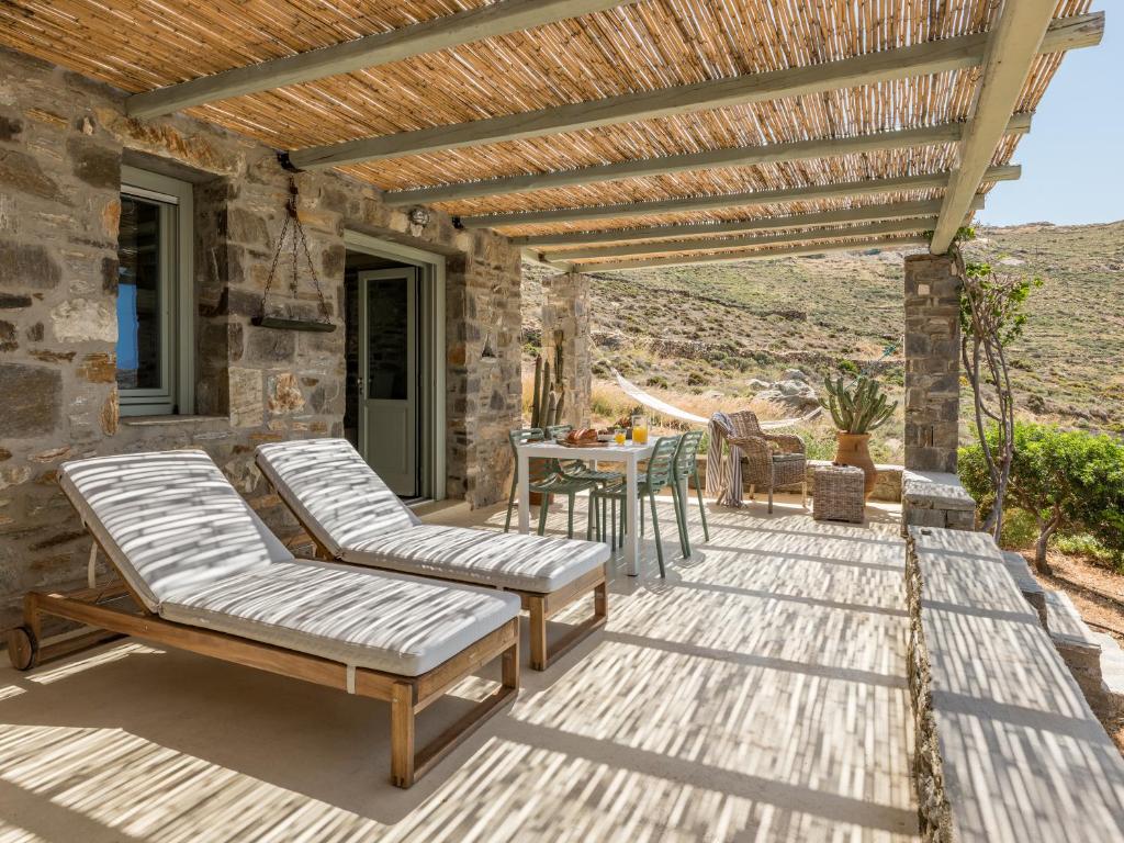 a patio with two lounge chairs and a table at Serifos Dream Houses near the sea in Ganema