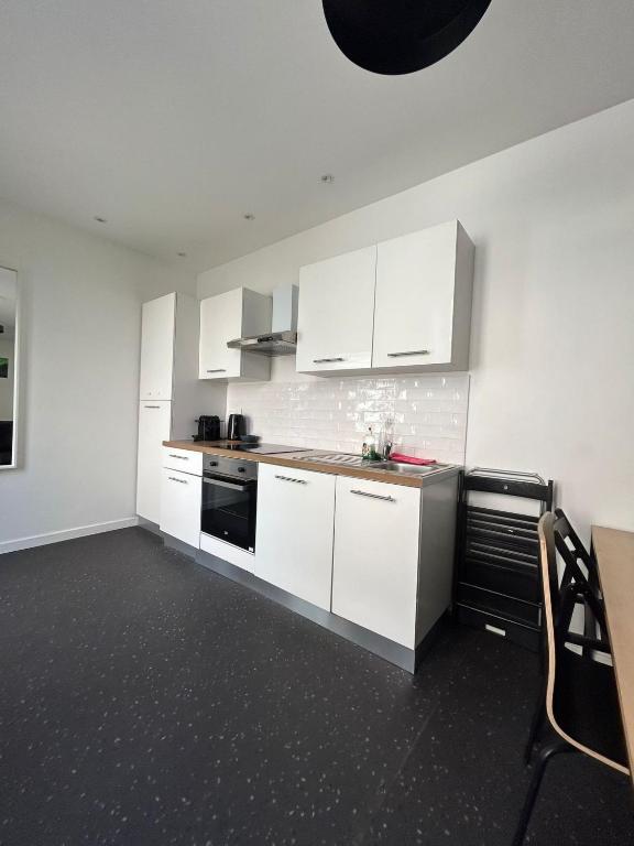 - une cuisine blanche avec des placards blancs et une table dans l'établissement Tromso - 6P - Hyper-centre - Agréable et Paisible, à Reims