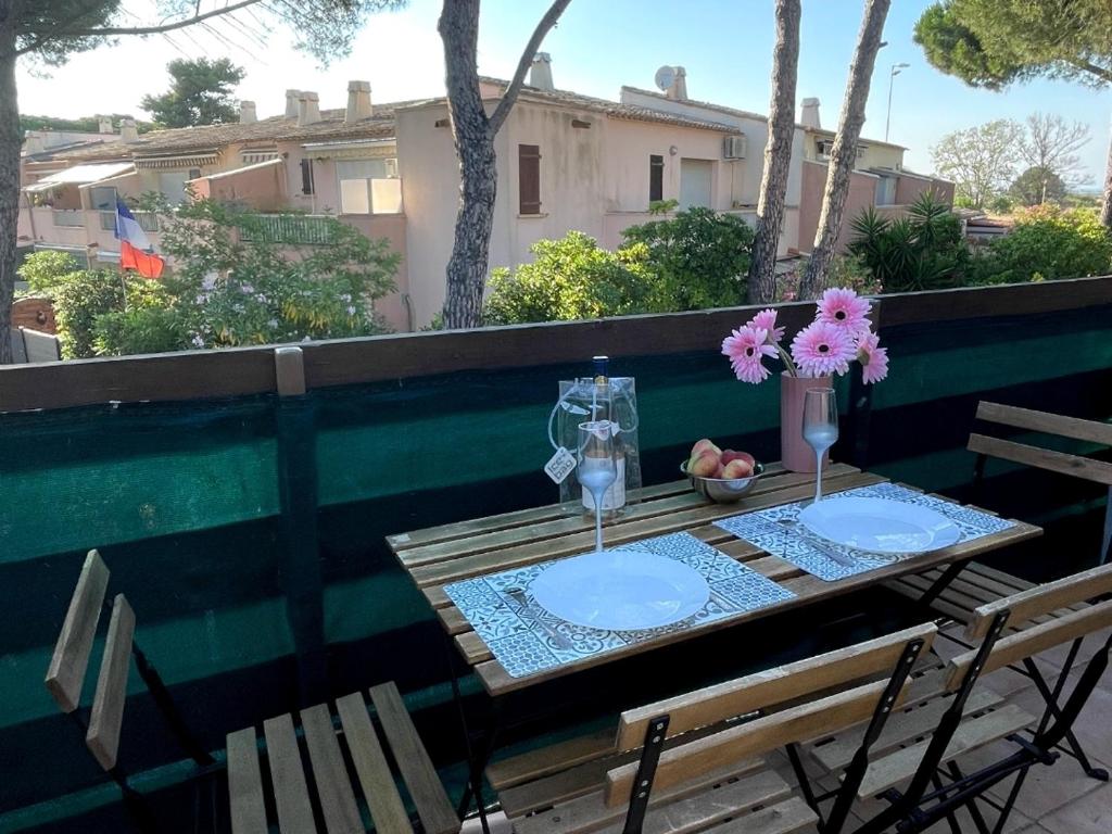 - une table avec deux verres et des fleurs sur un balcon dans l'établissement Appartement tout équipé village naturiste à 100 m, au Cap d'Agde