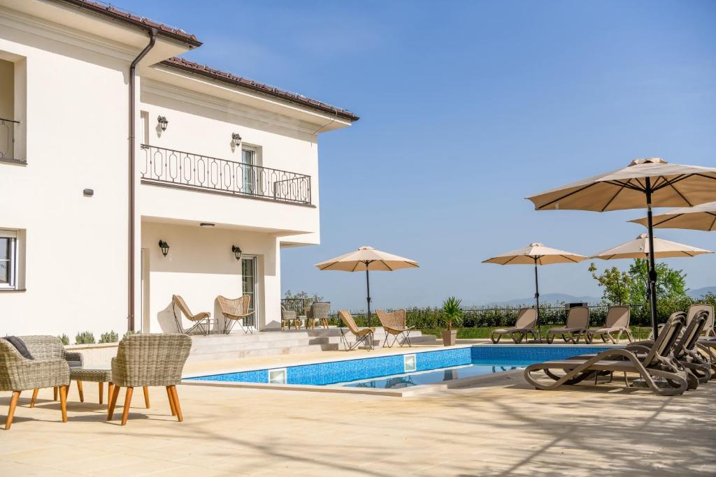 a villa with a swimming pool with chairs and umbrellas at Vila sa bazenom Vrnjačka Idila in Vrnjačka Banja