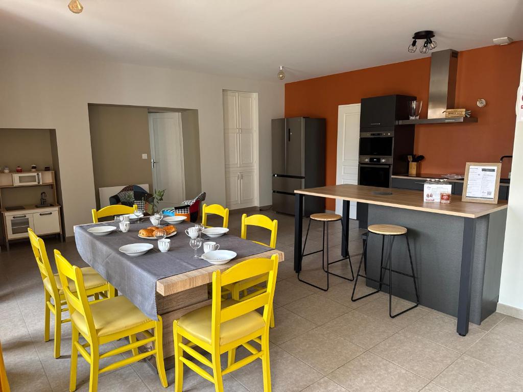 a kitchen and dining room with a table and yellow chairs at Gîte du Puits Olivier 10 personne chaleureux 3 étoiles in Airvault