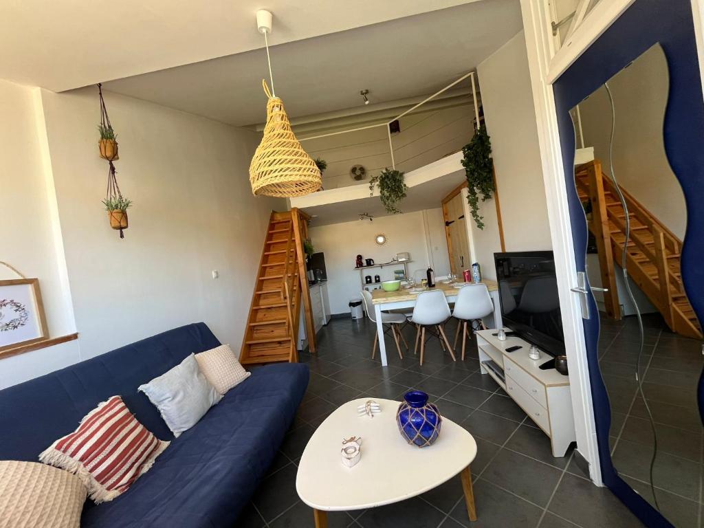un salon avec un canapé bleu et une table dans l'établissement Cocon pour les vacances à la mer NP, à Narbonne-Plage