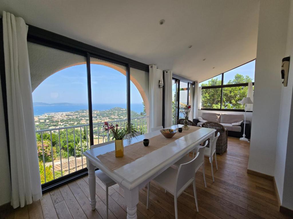 a dining room with a table and large windows at Jardin d azur Magnifique vue mer et piscine in Cavalaire-sur-Mer
