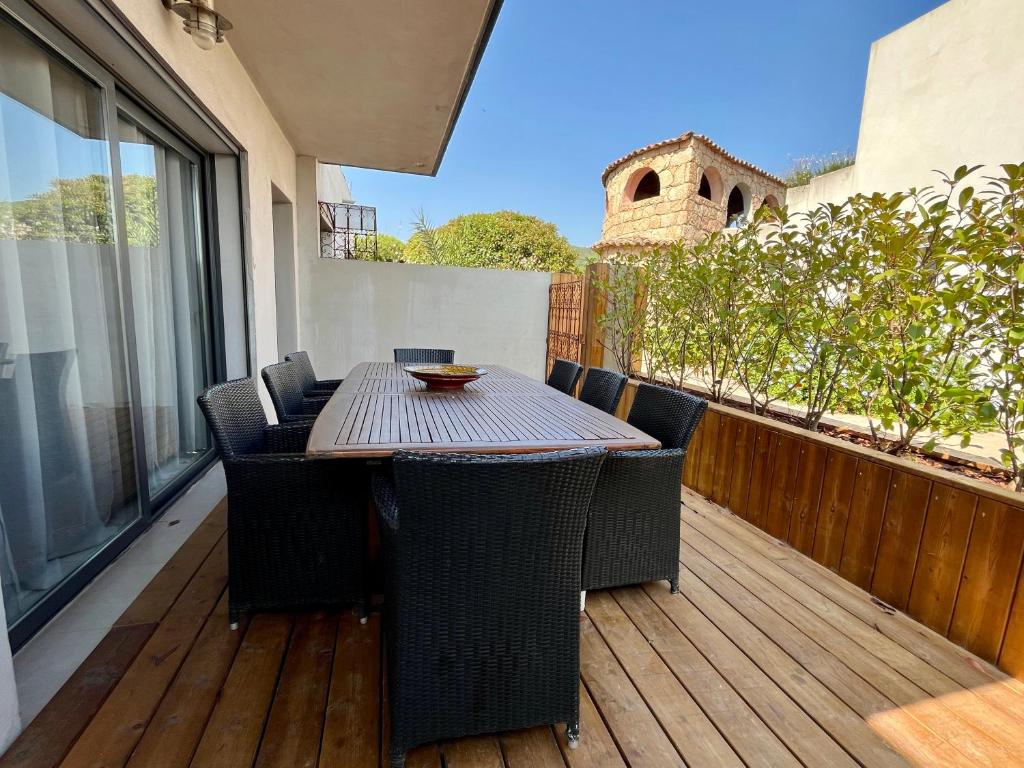 Una terraza de madera con una mesa y sillas en un balcón. en Résidence Storia di Blue, en Porto Vecchio