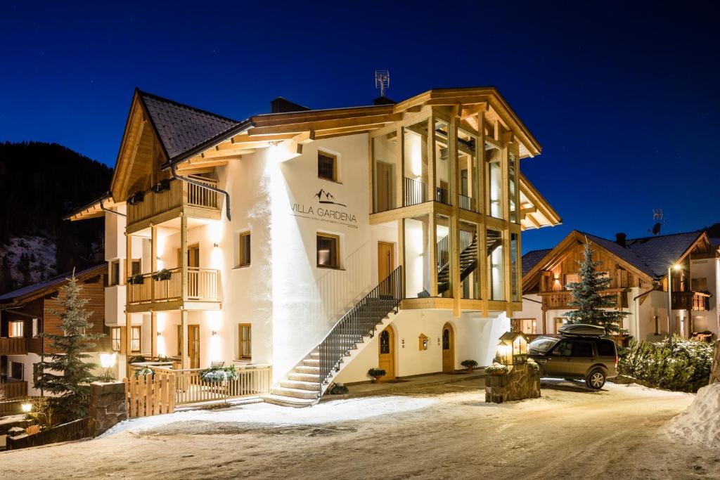 ein großes weißes Gebäude mit Treppen im Schnee in der Unterkunft Apartments Villa Gardena - Gardenahotels in Wolkenstein in Gröden