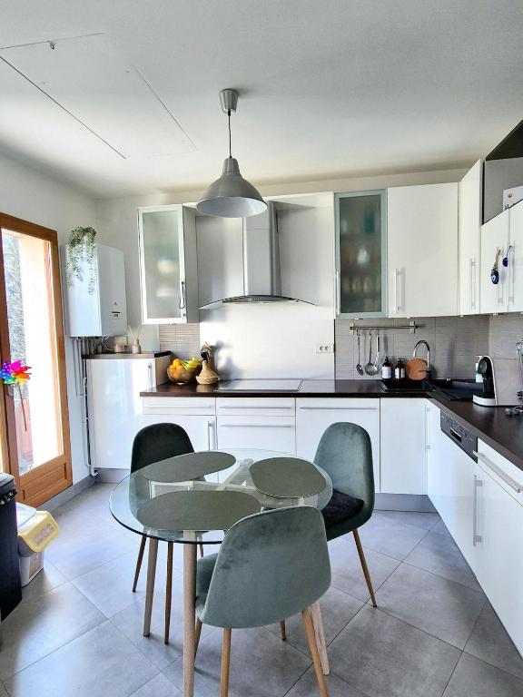 une cuisine avec des armoires blanches et une table et des chaises dans l'établissement F3 60 m2 - Paris Villejuif - Orly - Parking, à Villejuif