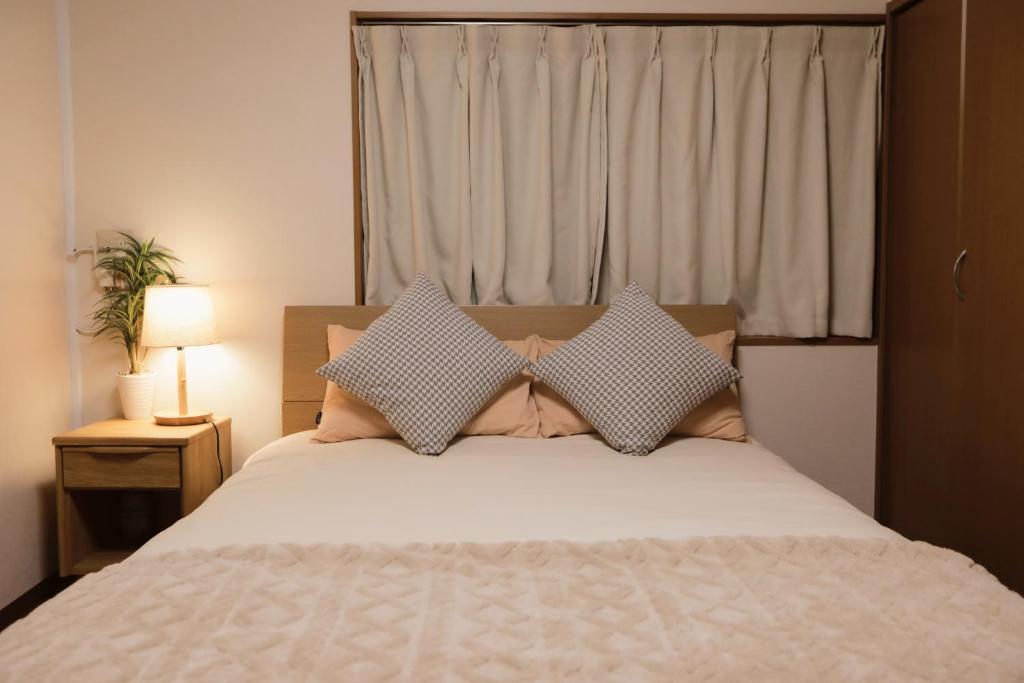 Un dormitorio con una cama con sábanas y almohadas blancas. en 貸切 一戸建て古民家 3部屋 静か, en Osaka
