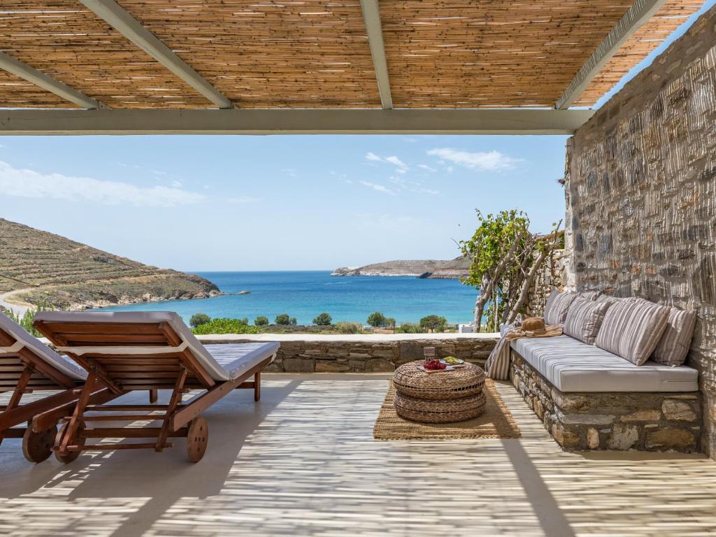 a patio with a couch and chairs and the ocean at Serifos Dream Houses near the sea in Ganema