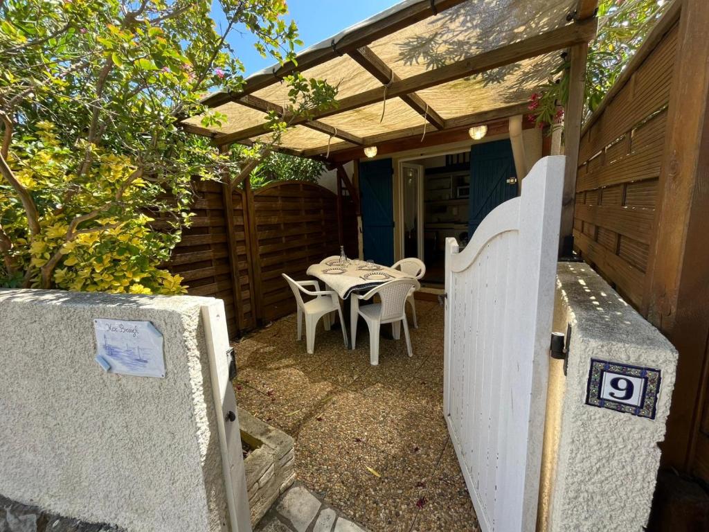 un patio avec une table et des chaises sous une pergola dans l'établissement Pavillon Eaux Vives à Saint Pierre La Mer, à Saint Pierre La Mer