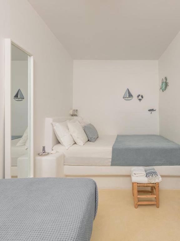 a white bedroom with two beds and a mirror at Serifos Dream Houses near the sea in Ganema