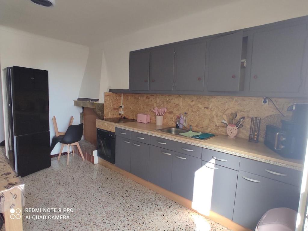 a kitchen with blue cabinets and a black refrigerator at Maison entre terre et Mer a proximité d'Argelès sur mer, collioure,Perthus,Espagne in Passa
